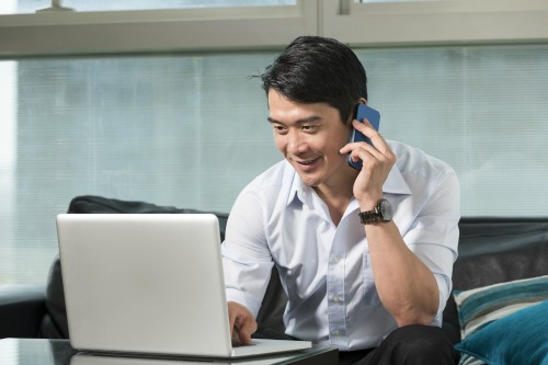 Chinese business man talking on a mobile phone and working on his laptop